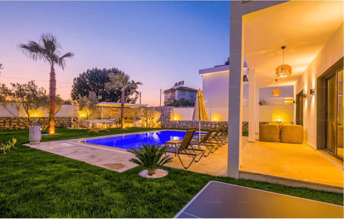 A contemporary villa with a landscaped garden and swimming pool at dusk